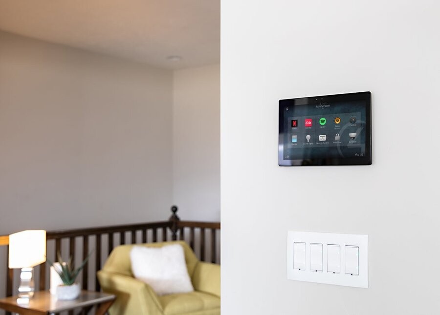 A living space in the background with a Control4 wall panel in focus in the foreground