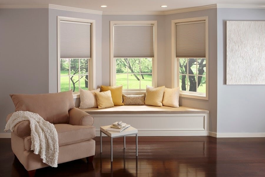  A couch in front of three windows featuring Lutron motorized blinds.